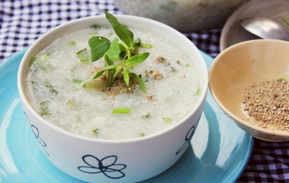 A steaming bowl of chao mac nhung garnished with spring onion and sliced chili
